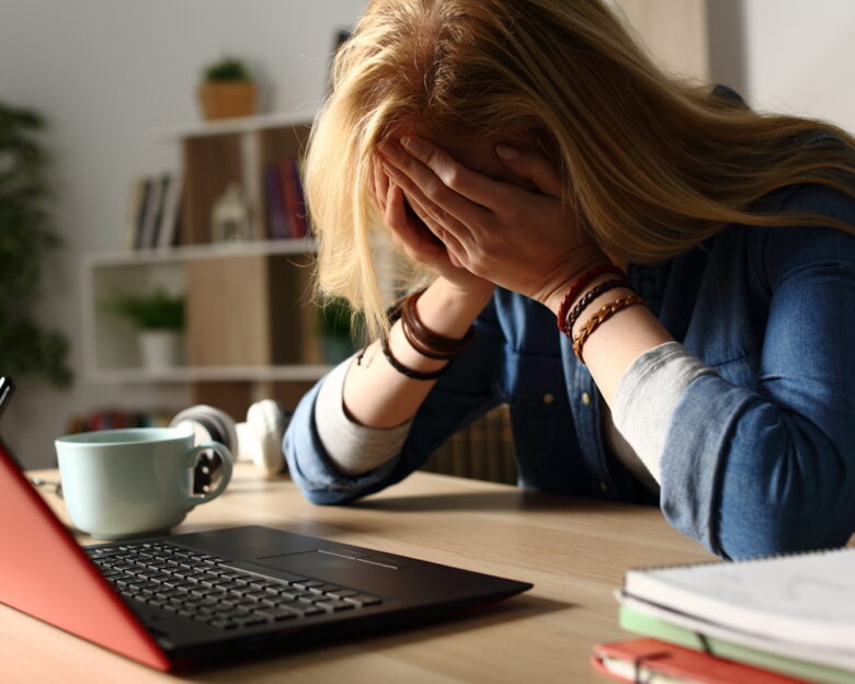 Close up of sad student receiving bad news on laptop sitting on a desk at home at night