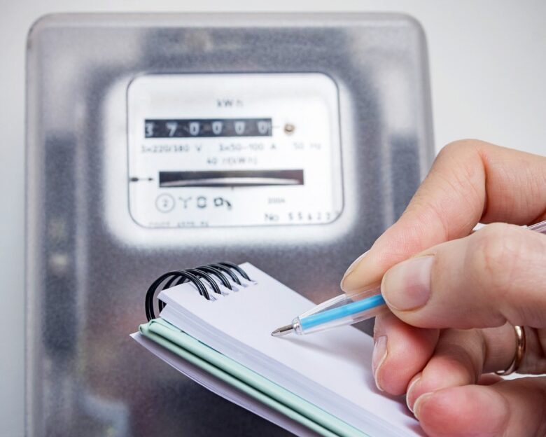 Woman with pen and notepad writes the electricity meter readings. Payment of utility services