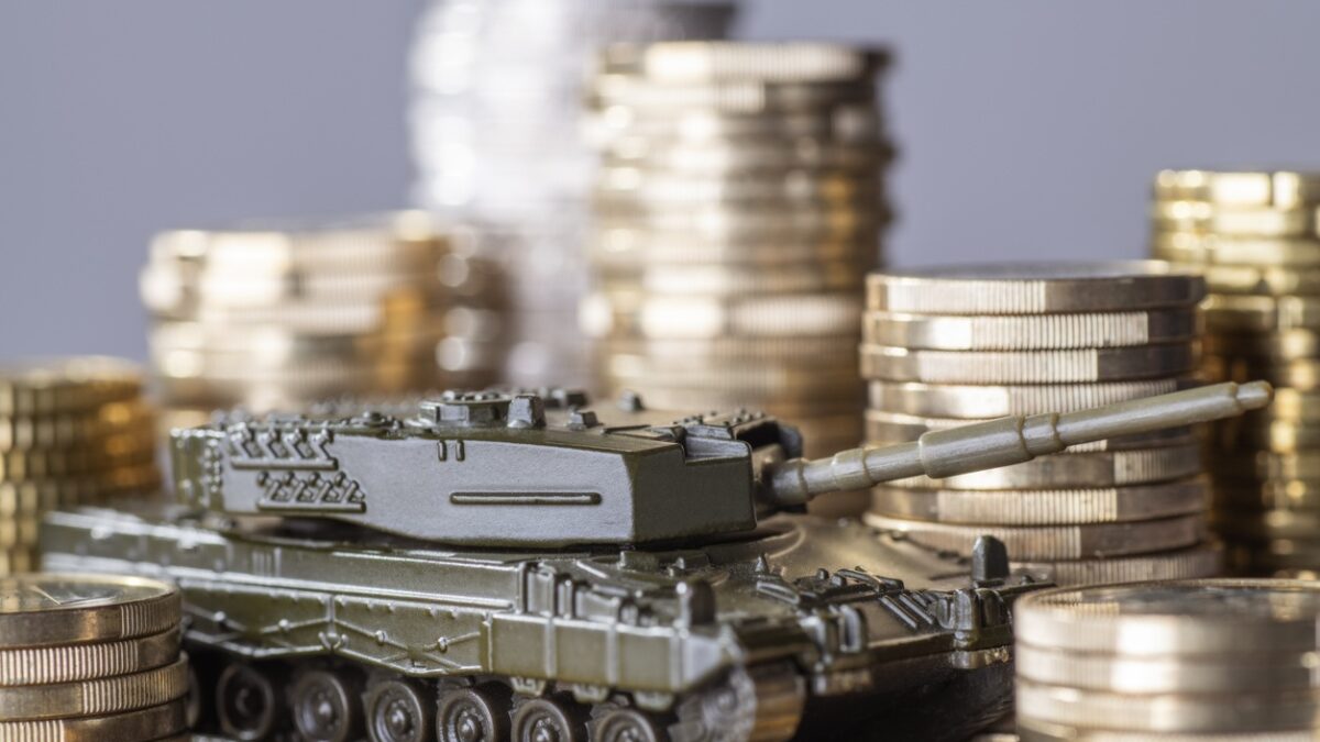 Tank between stacks of coins as a symbol of high armament expenditure