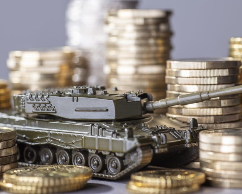 Tank between stacks of coins as a symbol of high armament expenditure