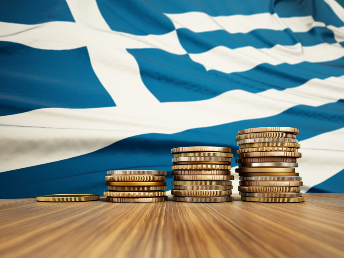 Rising stack of coins with Greek flag in the background. Economy, finance, interest rates concept.
