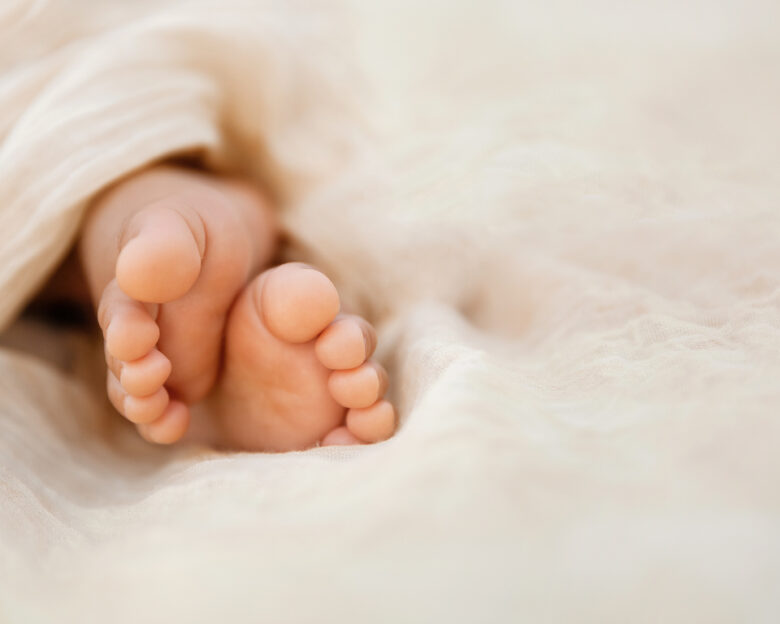 Newborn baby feet closeup on soft cream wrap in a selective focus - Image
