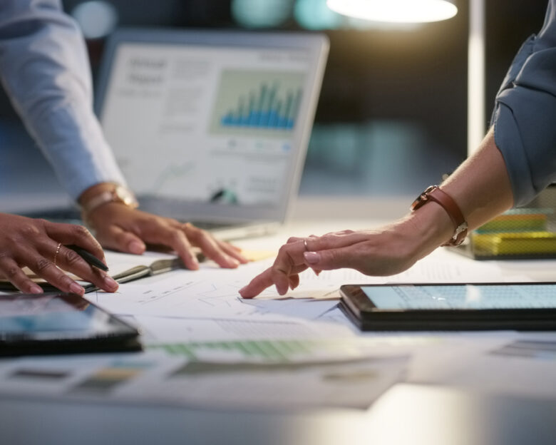 People, meeting and night graphs or laptop data analysis, for statistics research, budget report or teamwork. Business, group hands and documents, paperwork or computer screen for planning of charts