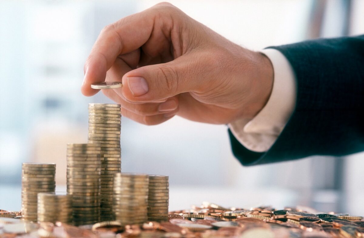 Hand of a mid adult man, wearing a siut, is stacking Euro coins.