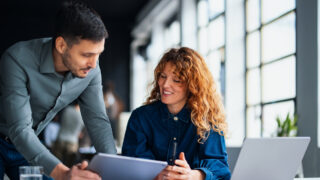 Colleagues discussing and sharing insights during a teamwork session, fostering productivity in a contemporary office setting. They appear engaged and motivated, embodying a positive and cooperative workplace environment.