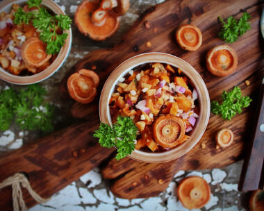 salad of fresh saffron milk caps with red onion and fresh parsley and whole mushrooms on a wooden Board