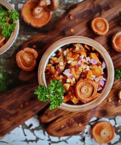 salad of fresh saffron milk caps with red onion and fresh parsley and whole mushrooms on a wooden Board