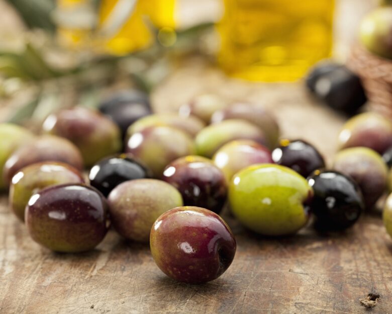 Green and black olives on old table.