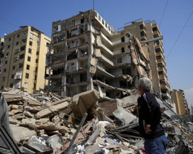 A man stands next to a damaged building in the aftermath of Israeli strikes, amid an escalation between Hezbollah and Israel, amid the U.S.-Israeli conflict with Iran, in Beirut's southern suburbs, Lebanon, March 12, 2026. REUTERS