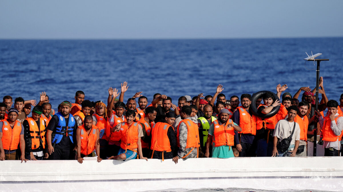 FILE PHOTO: Migrants standing on a fiberglass boat wave at NGO Open Arms rescue boat "Astral" as they assist them in international waters south of Lampedusa, in the Mediterranean Sea, July 24, 2025. REUTERS/Ana Beltran/File Photo