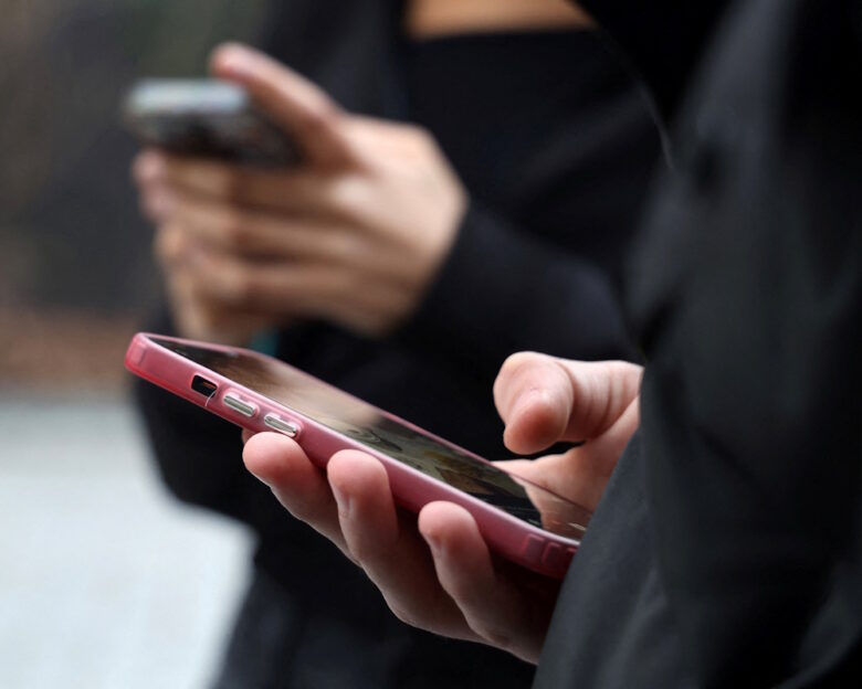 Teenagers look at their mobile phone screens during an interview with Reuters about the bill aimed at banning the use of social networks for those under 15 and mobile phones in high schools from the start of the 2026 school year, in Paris, France, February 20, 2026. REUTERS/Manuel Ausloos