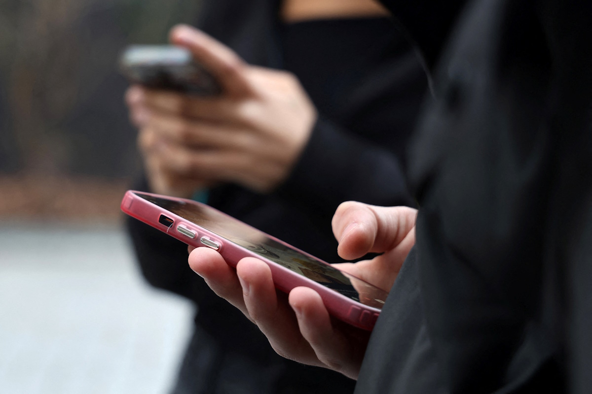 Teenagers look at their mobile phone screens during an interview with Reuters about the bill aimed at banning the use of social networks for those under 15 and mobile phones in high schools from the start of the 2026 school year, in Paris, France, February 20, 2026. REUTERS/Manuel Ausloos