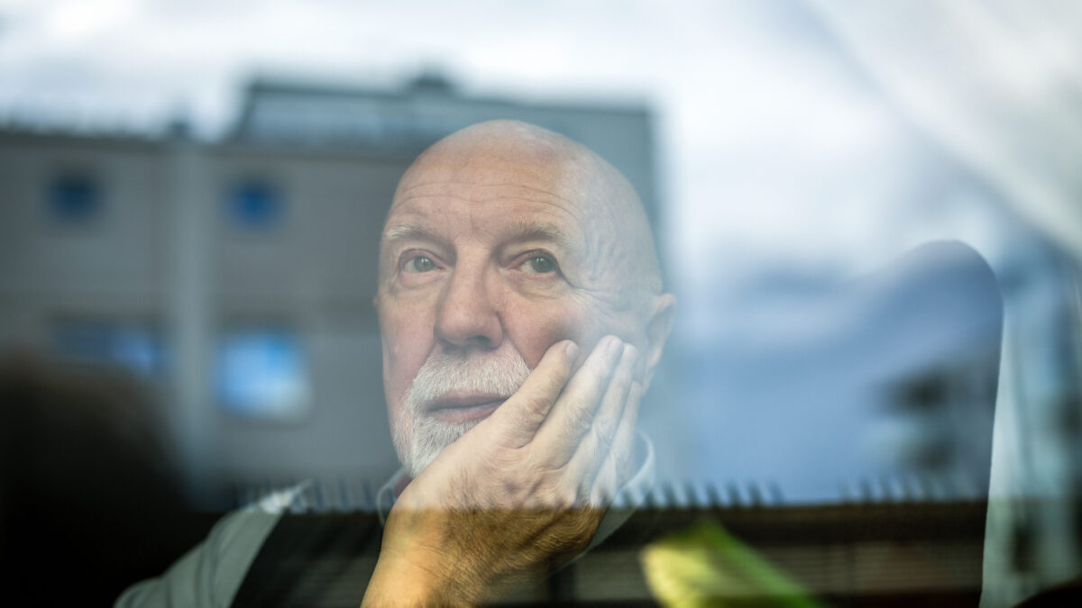 Portrait of thoughtful senior man looking through window