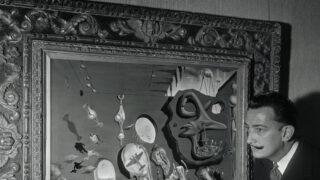 (Original Caption) Salvador Dali (right) points to figures on his new canvas, called Uranium and Atomica Melancholia Idyll, currently on display at the Bignou Gallery, 32 East 57th Street. Atoms burst all over the canvas which contains, among other things, sliding baseball players, an umpire, a catcher, and the artist's characteristic melted clocks.