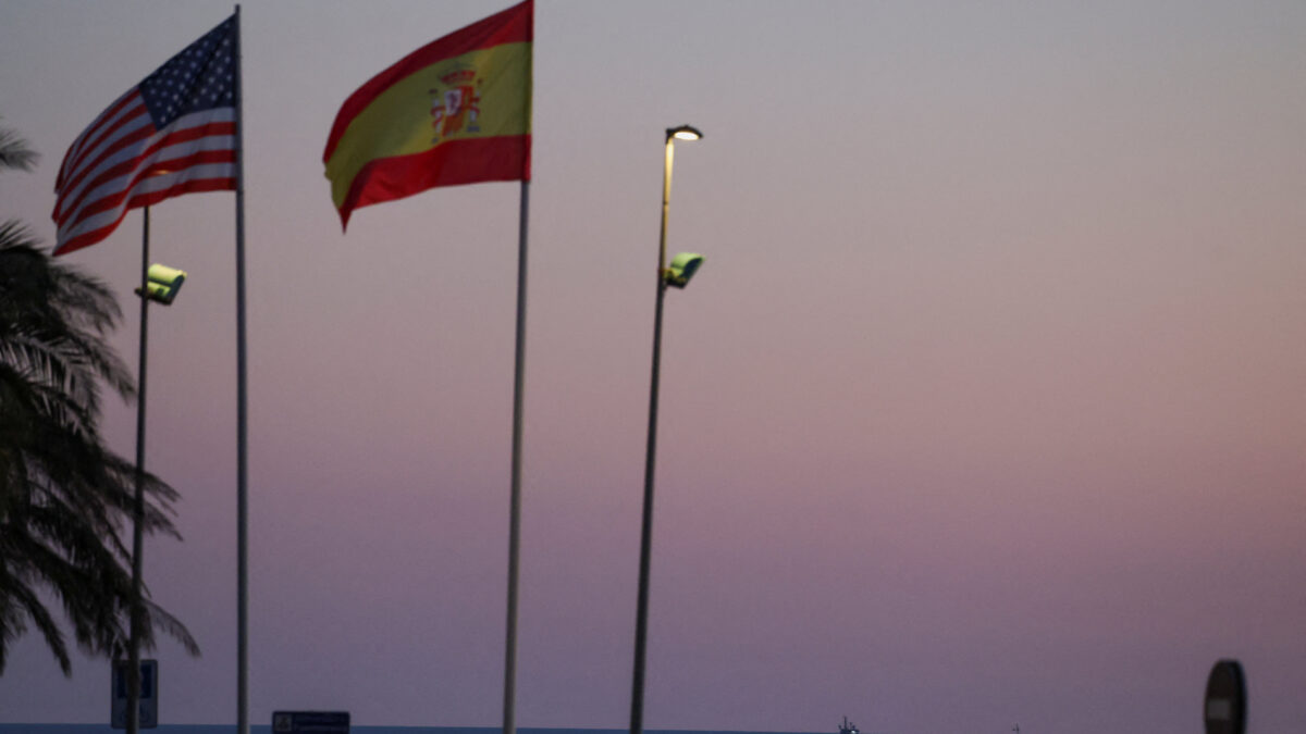 A cargo ship is anchored near the port of Algeciras at sunset, behind the flags of the United States and Spain on a roundabout near the jointly operated naval base in Rota, in the province of Cadiz, Spain March 15, 2026. REUTERS/Nacho Doce