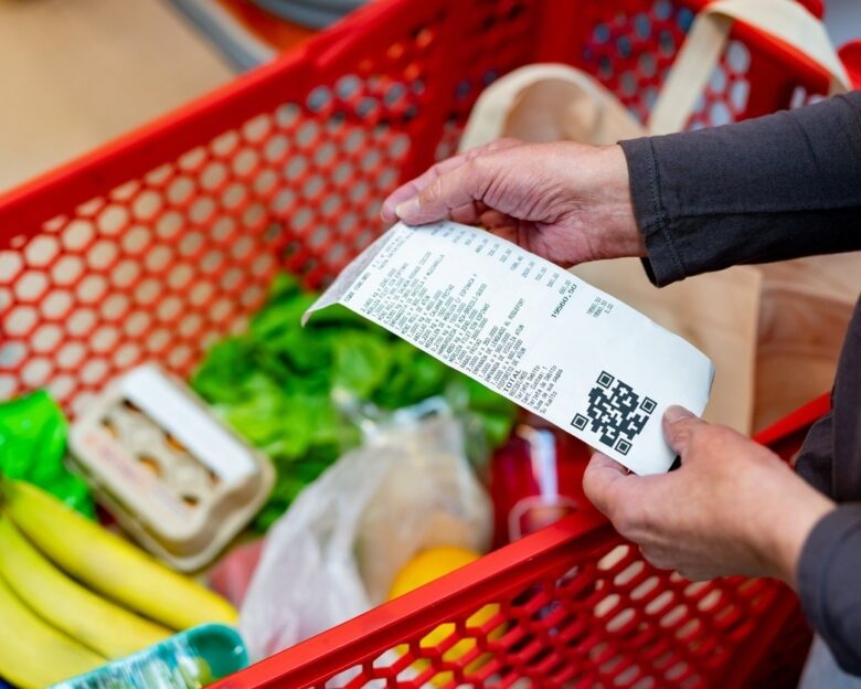 Close up of unrecognizable customer checking her receipt after purchasing groceries in the supermarket - Home shopping concepts