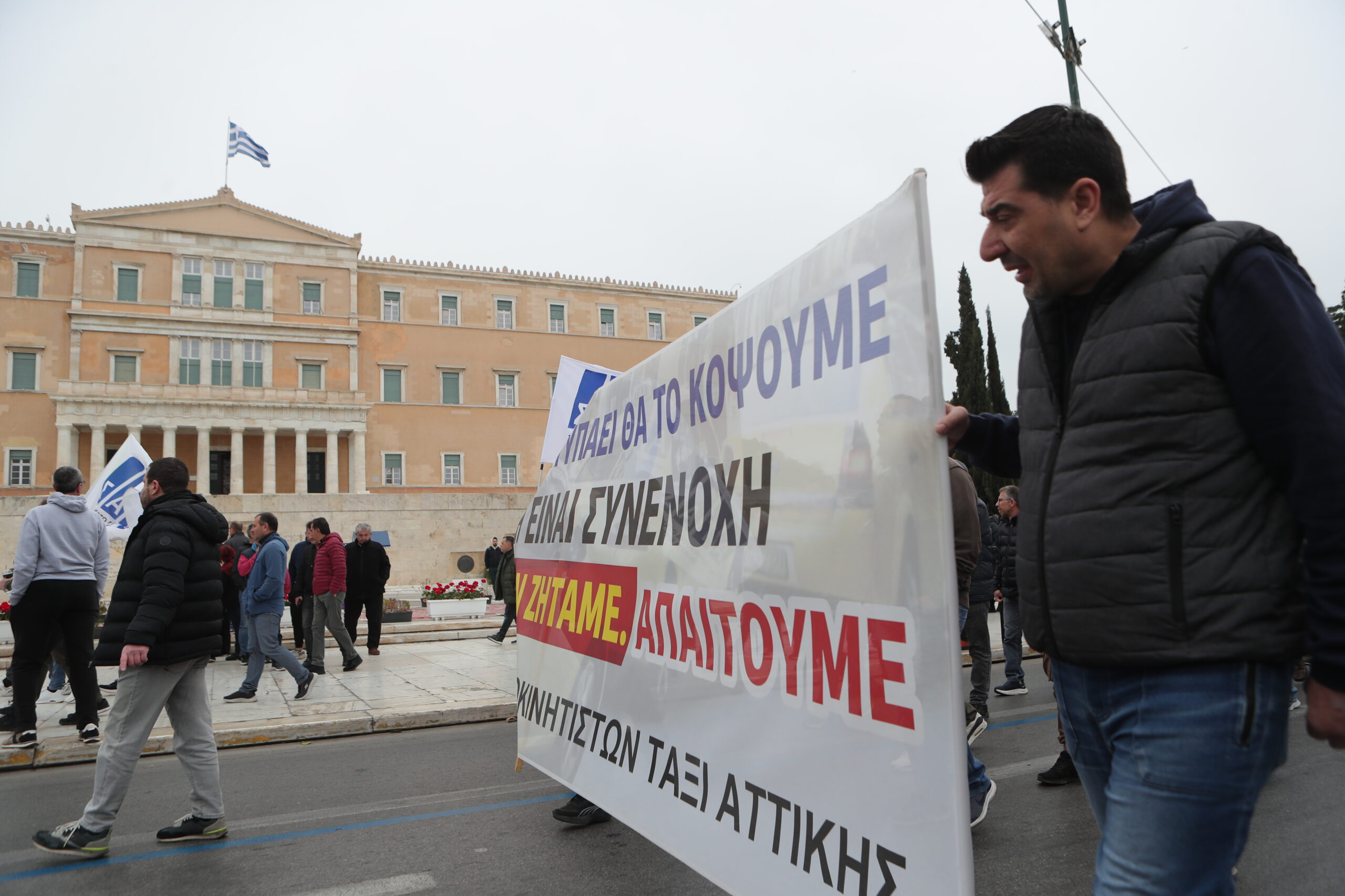 Απεργιακή συγκέντρωση αυτοκινητιστών ταξί της Αττικής, στα γραφεία του ΣΑΤΑ και πορεία στην πλατεία Συντάγματος, Τρίτη 17 Μαρτίου 2026. Οι επαγγελματίες αυτοκινητιστές αντιδρούν σε διατάξεις του νομοσχεδίου για την ηλεκτροκίνηση και ξεκίνησαν εικοσιτετράωρες, επαναλαμβανόμενες απεργιακές κινητοποιήσεις. Ανάμεσα στα αιτήματά τους είναι η παράταση του μέτρου για την ηλεκτροκίνηση που προωθεί το αρμόδιο υπουργείο μέχρι το 2035, καθότι υποστηρίζουν πως είναι πολύ ακριβά τα οχήματα και δεν υπάρχουν και οι υποδομές ώστε να καλυφθούν οι ανάγκες αυτών των οχημάτων. Στο επίκεντρο της αντιπαράθεσης με την κυβέρνηση είναι και το άρθρο 52 που αφορά τα επιβατικά ιδιωτικής χρήσης με οδηγό. Οι εκπρόσωποι των ταξί υποστηρίζουν πως αυτή η ρύθμιση, ανοίγει το δρόμο σε εταιρείες ενοικιαζομένων με οδηγό, δημιουργώντας, όπως λένε, συνθήκες αθέμιτου ανταγωνισμού καθώς θα πραγματοποιούν αστικές κούρσες.   (ΣΩΤΗΡΗΣ ΔΗΜHΤΡΟΠΟΥΛΟΣ