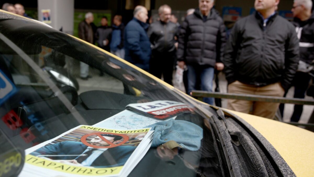 Αφίσα που απεικονίζει τον αναπληρωτή υπουργό Μεταφορών Κώστα Κυρανάκη, φαίνεται πίσω από το τζάμι ταξί κατά τη διάρκεια διαμαρτυρίας και απεργίας αορίστου χρόνου του συνδικάτου ΣΑΤΑ