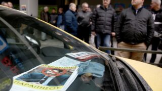 Αφίσα που απεικονίζει τον αναπληρωτή υπουργό Μεταφορών Κώστα Κυρανάκη, φαίνεται πίσω από το τζάμι ταξί κατά τη διάρκεια διαμαρτυρίας και απεργίας αορίστου χρόνου του συνδικάτου ΣΑΤΑ