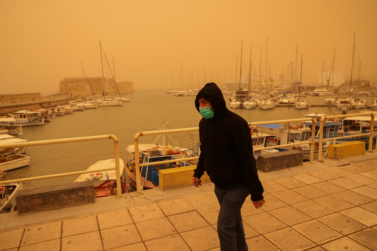 A man protects himself with a face mask, while walking in a haze caused by sand dust from the Sahara, due to strong southern winds, in Heraklion, Crete island, Greece April 1, 2026. REUTERS