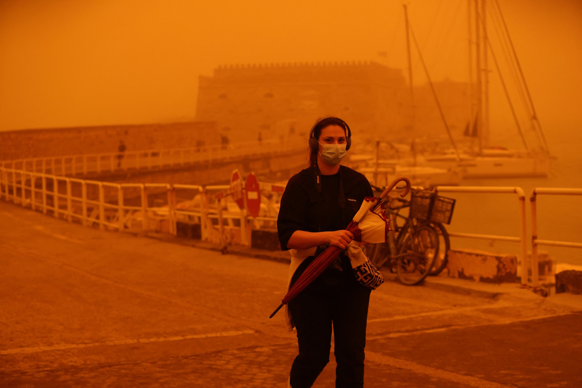 A woman protects herself with a face mask while walking in a haze caused by sand dust from the Sahara, due to strong southern winds, in Heraklion, Crete island, April 1, 2026. REUTERS