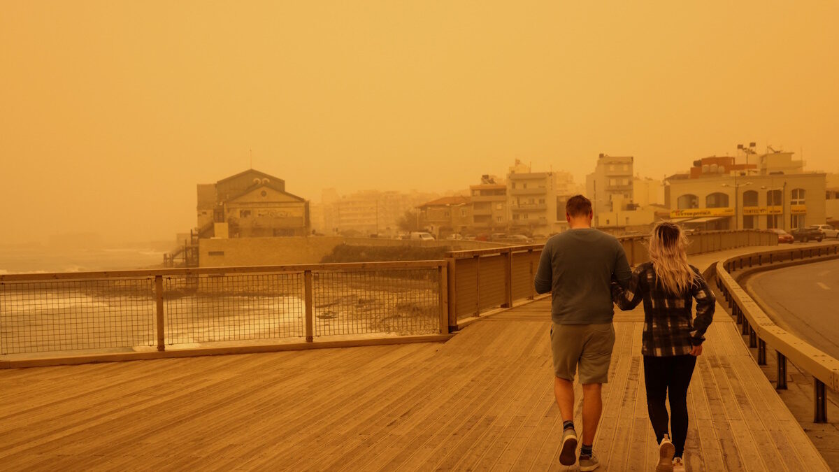 People walk in a haze, caused by sand dust from the Sahara, due to strong southern winds, in Heraklion, Crete island, Greece, April 1, 2026. REUTERS