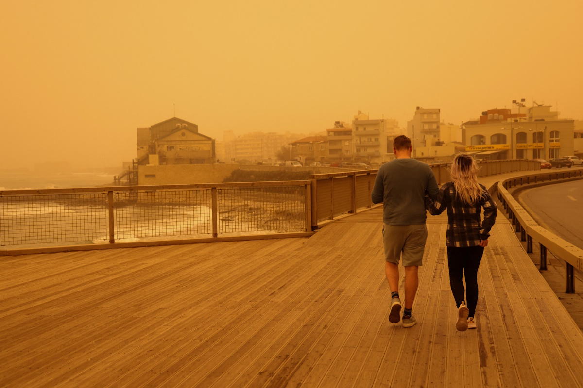 People walk in a haze, caused by sand dust from the Sahara, due to strong southern winds, in Heraklion, Crete island, Greece, April 1, 2026. REUTERS