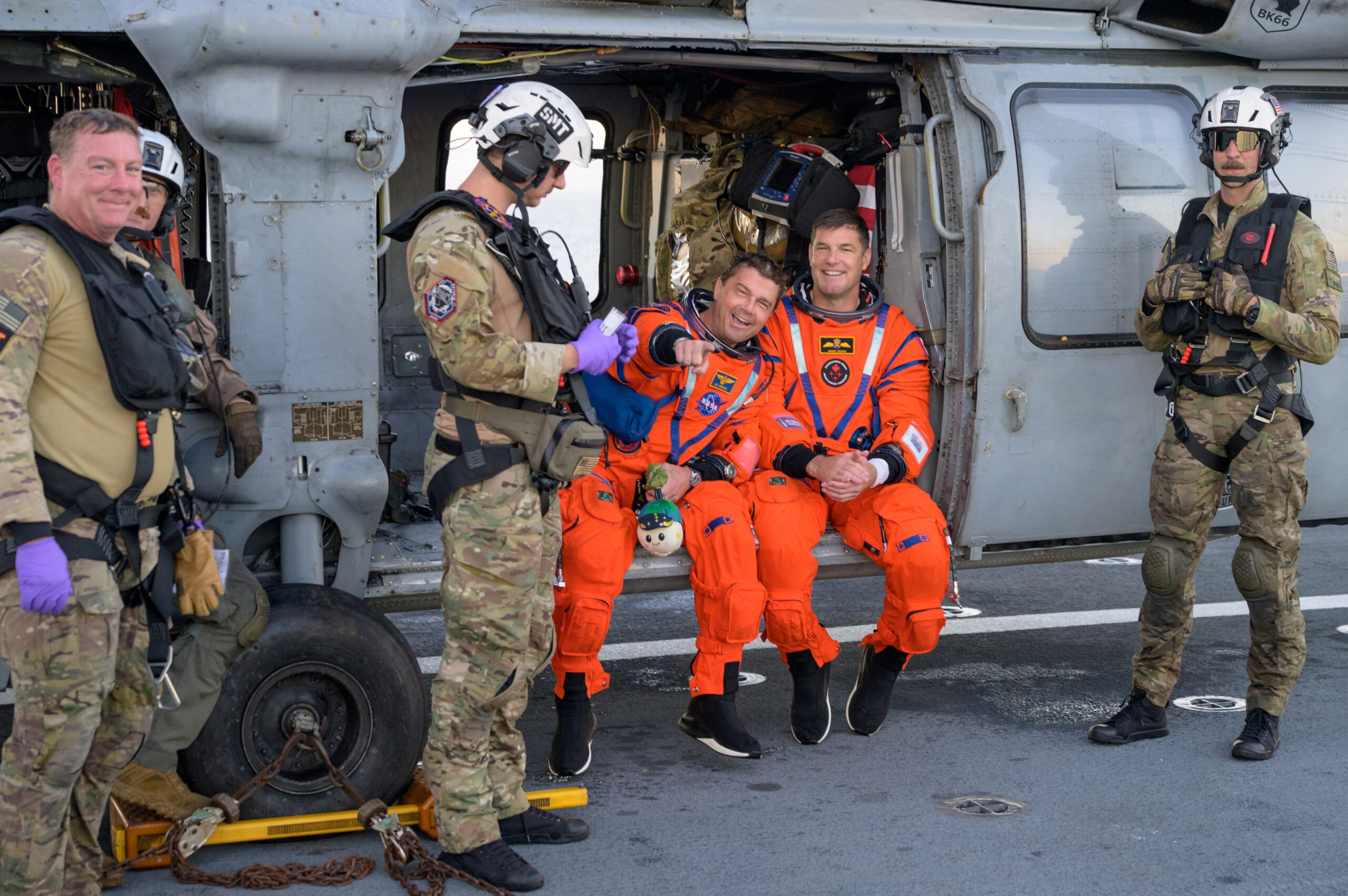NASA astronaut Reid Wiseman, Artemis II commander, and CSA (Canadian Space Agency) astronaut Jeremy Hansen, Artemis II mission specialist react while sitting on a Navy MH-60 Seahawk from Helicopter Sea Combat Squadron (HSC) 23 on the flight deck of USS John P. Murtha after they and fellow crewmates were extracted from their Orion spacecraft after splashdown, in the Pacific Ocean off the coast of California, U.S. April 10, 2026. NASA
