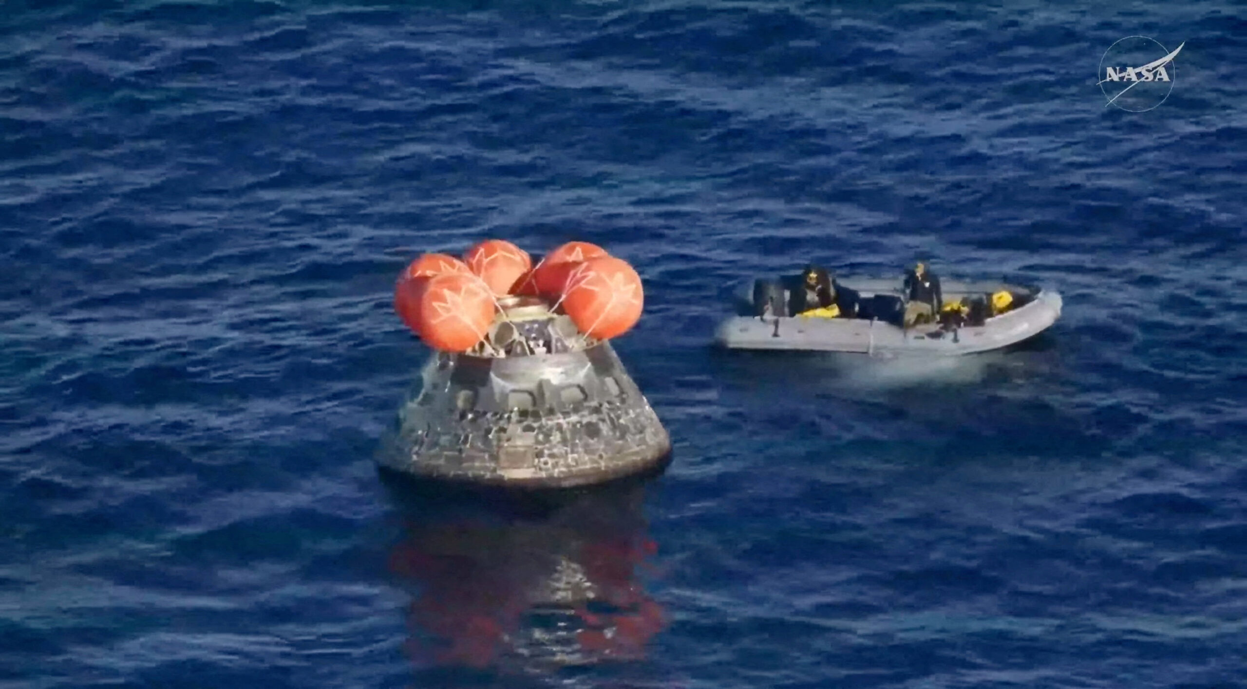A boat approaches the Artemis II crew capsule floating in the Pacific Ocean following splashdown in this screengrab from a livestream video after the Artemis II crew's flyby of the Moon, April 10, 2026. NASA