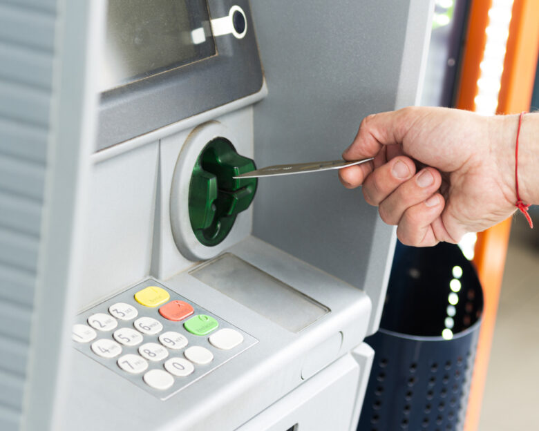 Human hand inserting a credit card into an ATM to withdraw money