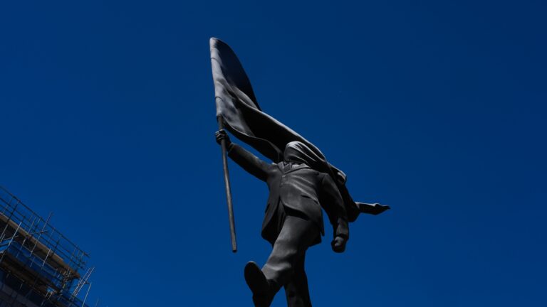 A statue of a man holding a flag covering his face, and signed 'Banksy', which has appeared in Waterloo Place in London, Thursday, April 30, 2026. (AP Photo/Kin Cheung)