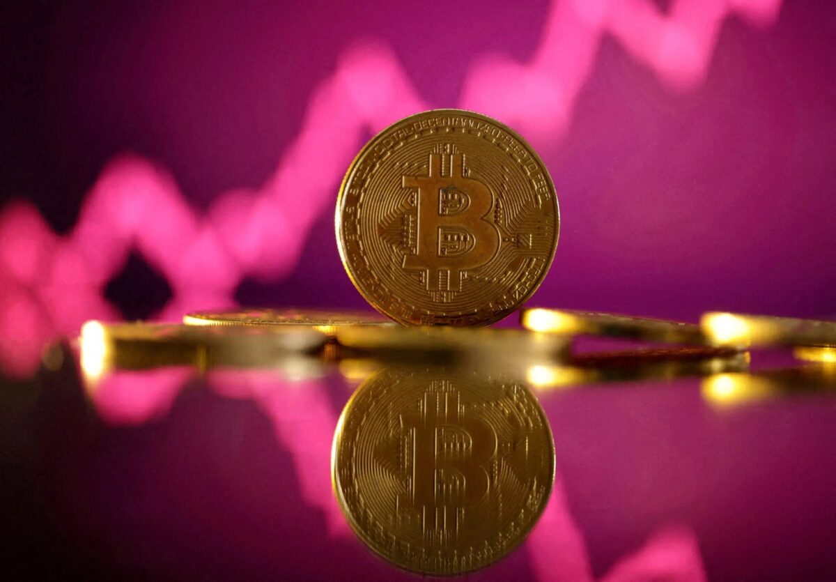 A representation of virtual currency Bitcoin is seen in front of a stock graph