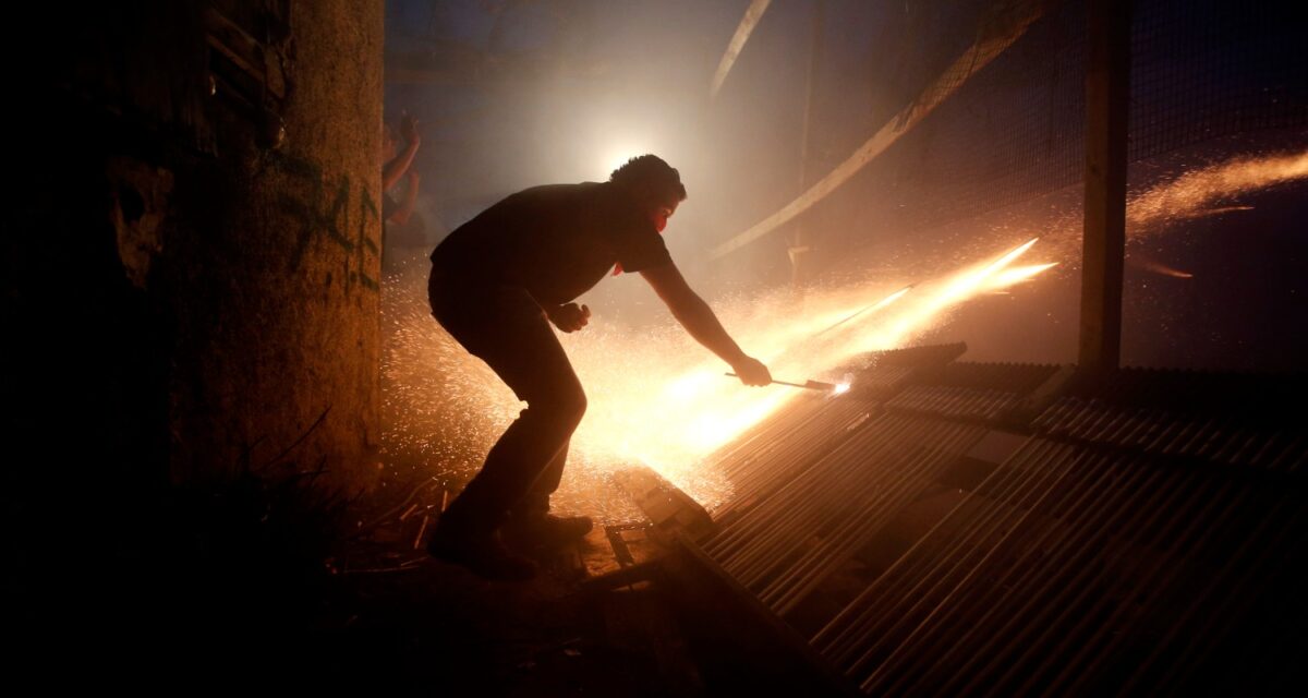 A man ignites rockets during Greek Orthodox Easter celebrations on the eastern Aegean island of Chios, Saturday , April 19, 2014.Thousands of handmade rockets are fired every year on Great Saturday night, a while before the Resurrection, by locals of the two rival churches of Agios Markos and Panagia Erithiani, in the village of Vrontados. The tradition is a 125-year-old one, but locals say it could be even older. (AP Photo/Petros Giannakouris)