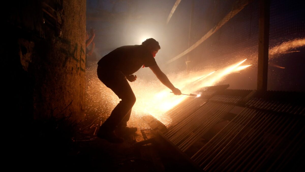 A man ignites rockets during Greek Orthodox Easter celebrations on the eastern Aegean island of Chios, Saturday , April 19, 2014.Thousands of handmade rockets are fired every year on Great Saturday night, a while before the Resurrection, by locals of the two rival churches of Agios Markos and Panagia Erithiani, in the village of Vrontados. The tradition is a 125-year-old one, but locals say it could be even older. (AP Photo/Petros Giannakouris)