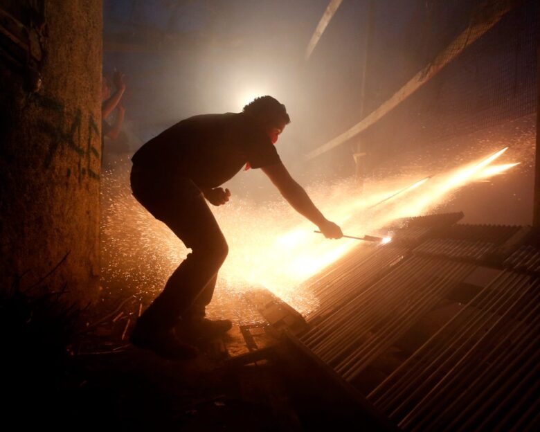 A man ignites rockets during Greek Orthodox Easter celebrations on the eastern Aegean island of Chios, Saturday , April 19, 2014.Thousands of handmade rockets are fired every year on Great Saturday night, a while before the Resurrection, by locals of the two rival churches of Agios Markos and Panagia Erithiani, in the village of Vrontados. The tradition is a 125-year-old one, but locals say it could be even older. (AP Photo/Petros Giannakouris)
