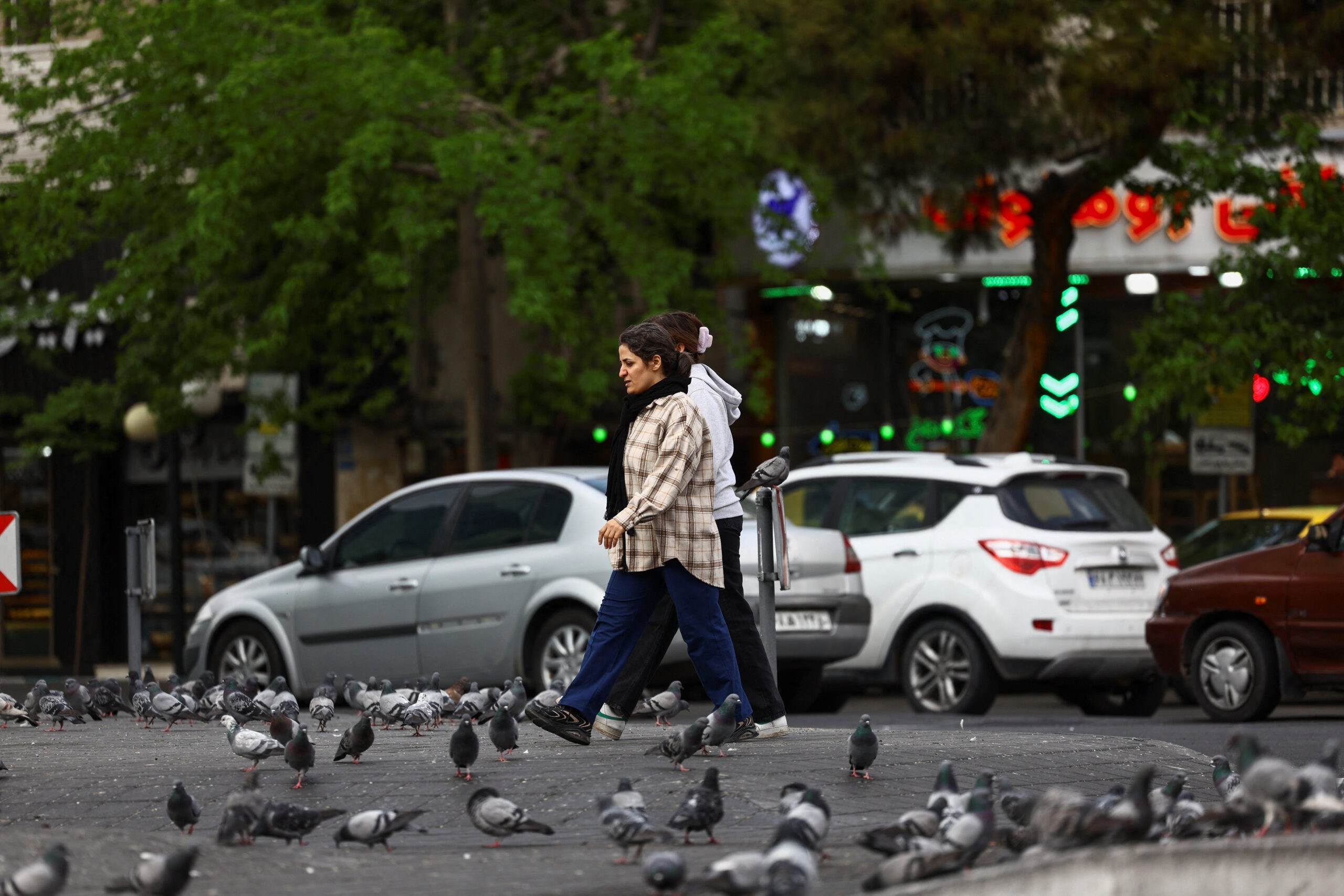 Iranian women walk next to birds in a street in Tehran, Iran, April 13, 2026. Majid Asgaripour/WANA (West Asia News Agency) via REUTERS ATTENTION EDITORS - THIS PICTURE WAS PROVIDED BY A THIRD PARTY