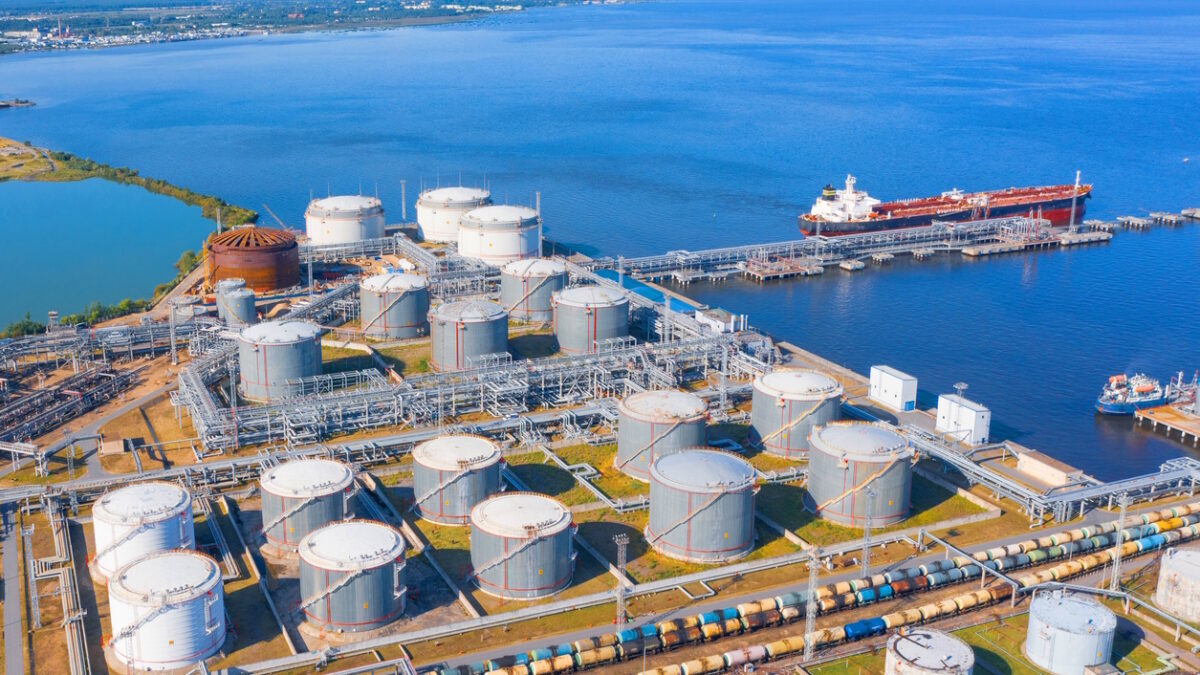Aerial view of large fuel storage tanks at oil refinery industrial zone in the cargo seaport, and ship tanker at unloading