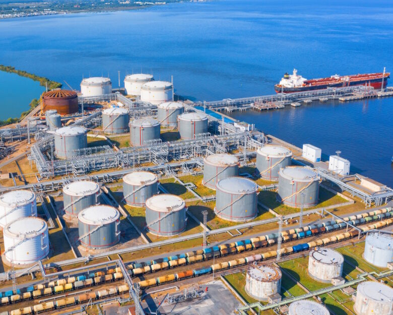Aerial view of large fuel storage tanks at oil refinery industrial zone in the cargo seaport, and ship tanker at unloading