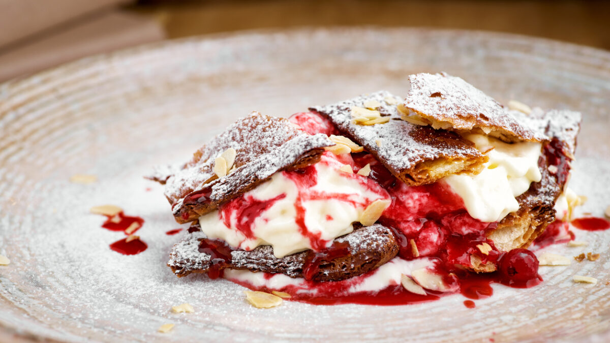 french dessert millefeuille of puff pastry and custard and ice cream on a plate and on a wooden table, close-up, macro.
