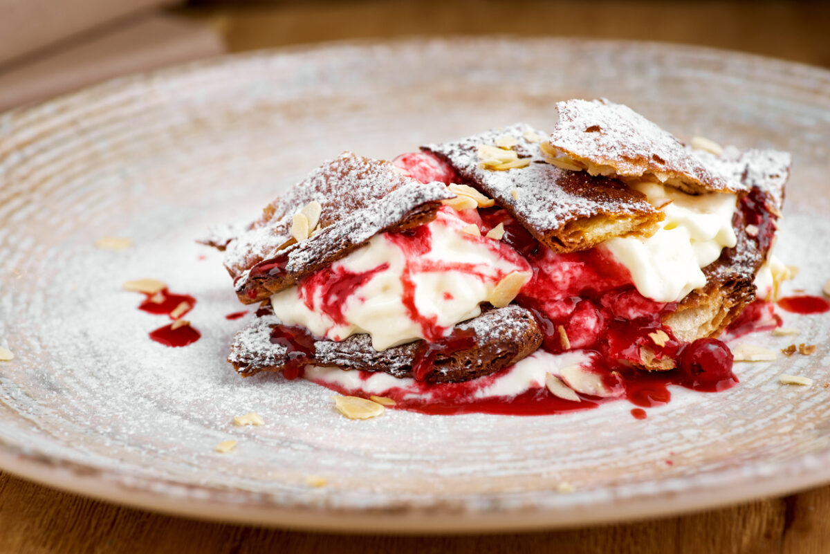 french dessert millefeuille of puff pastry and custard and ice cream on a plate and on a wooden table, close-up, macro.