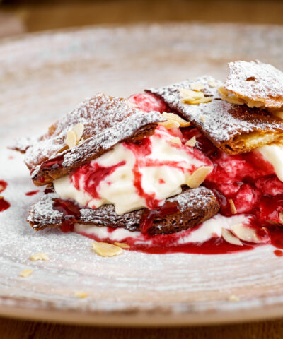 french dessert millefeuille of puff pastry and custard and ice cream on a plate and on a wooden table, close-up, macro.