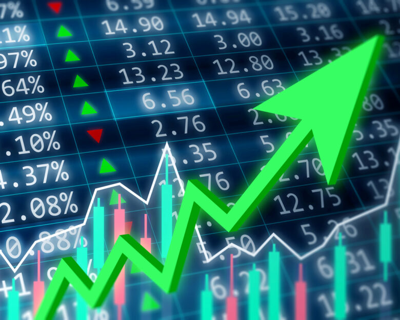 Stock market, financial and business concept. Financial data on a monitor with green arrow going up and red, green candle stick graph chart on dark background