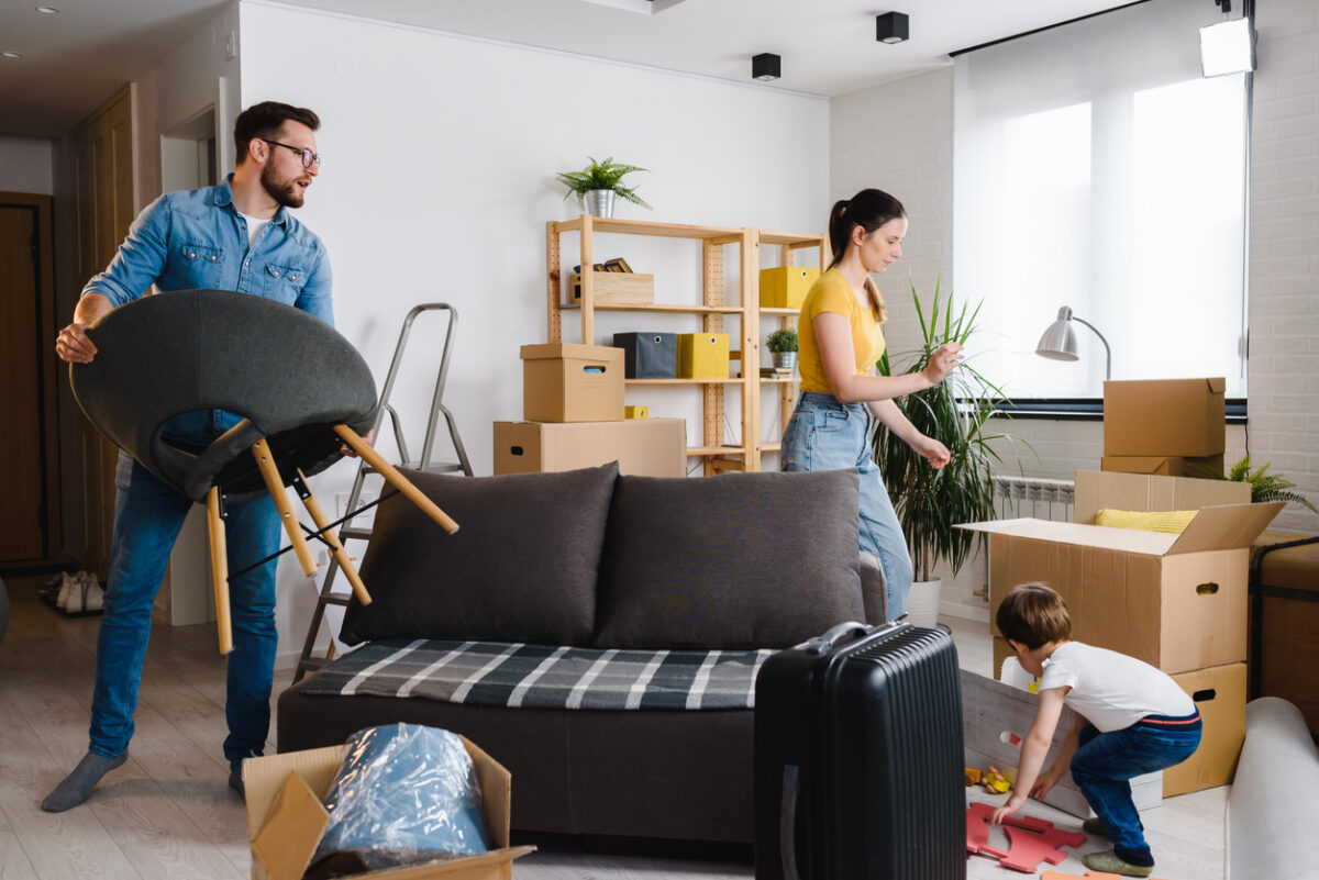 Happy young family husband, wife and toddler son just moved into new home unpacking. Relocation.