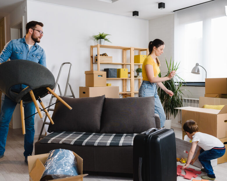 Happy young family husband, wife and toddler son just moved into new home unpacking. Relocation.