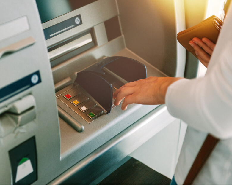 Woman using ATM holding wallet an pressing the PIN security number on the keyboard automatic teller machine