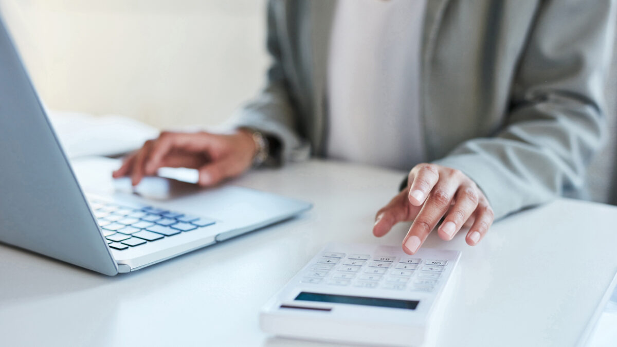 Closeup shot of an unrecognisable businesswoman using a calculator and laptop in an office