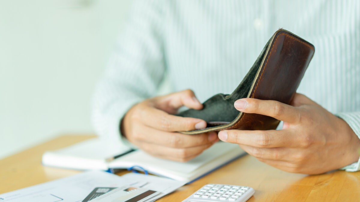 close up man hand opening empty wallet over calculator , debt expense bills monthly and credit card at the table in home office , managing payroll,money risk financial concept