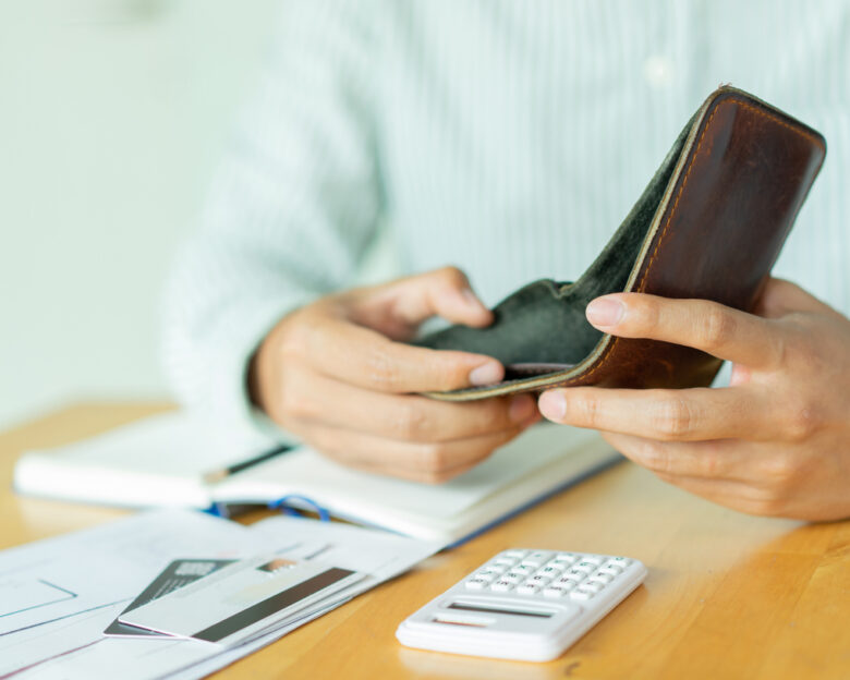 close up man hand opening empty wallet over calculator , debt expense bills monthly and credit card at the table in home office , managing payroll,money risk financial concept