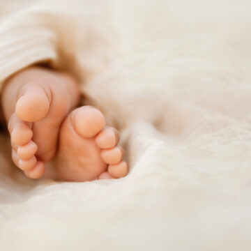 Newborn baby feet closeup on soft cream wrap in a selective focus - Image