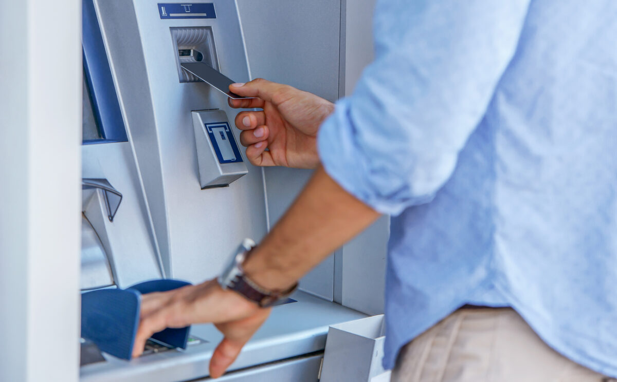 Man using a street ATM machine and withdrawing money, close up photo